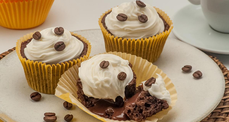 Imagem de um cupcake com graos de cafe e um pouco de chantilly.